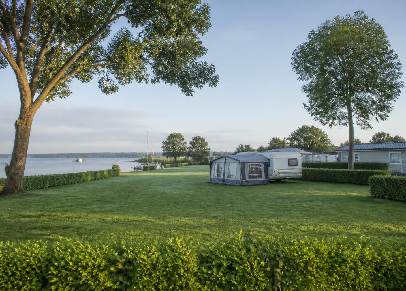 Rustig kampeerveld met caravan aan het water